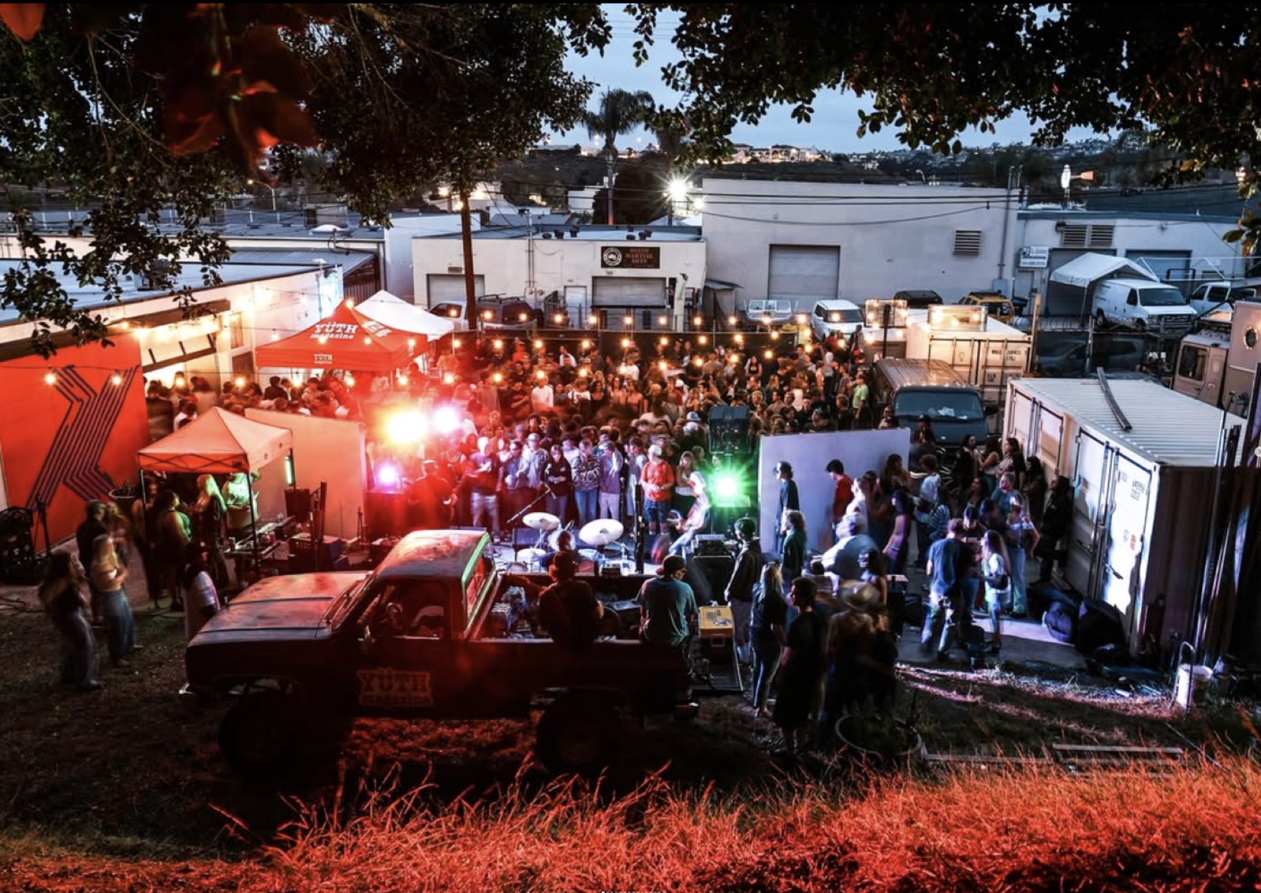 Packed night event in the Ficus yard — band, crowd and string lights